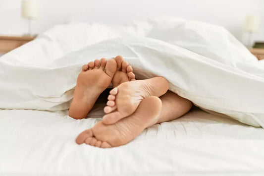 A man and woman’s feet peeking out from under a blanket during sex.