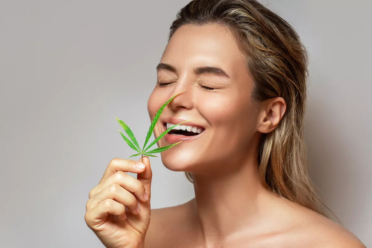 CBD skincare. Woman with a cannabis leaf on gray background