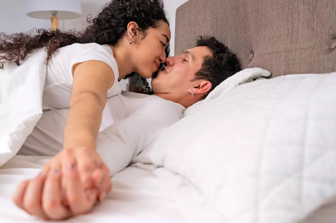 Couple sharing a tender moment in bedroom, embracing and holding hands.