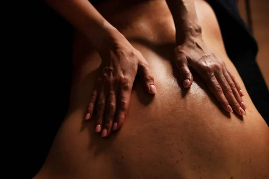Two hands on a glistening, oiled-up back.